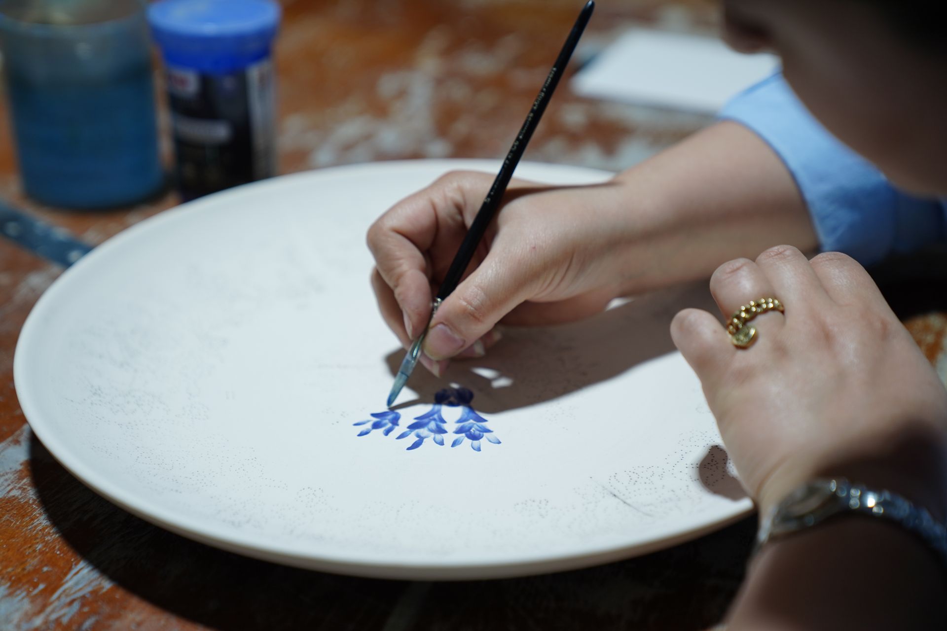 Artisan hand-painting blue floral details on a ceramic plate